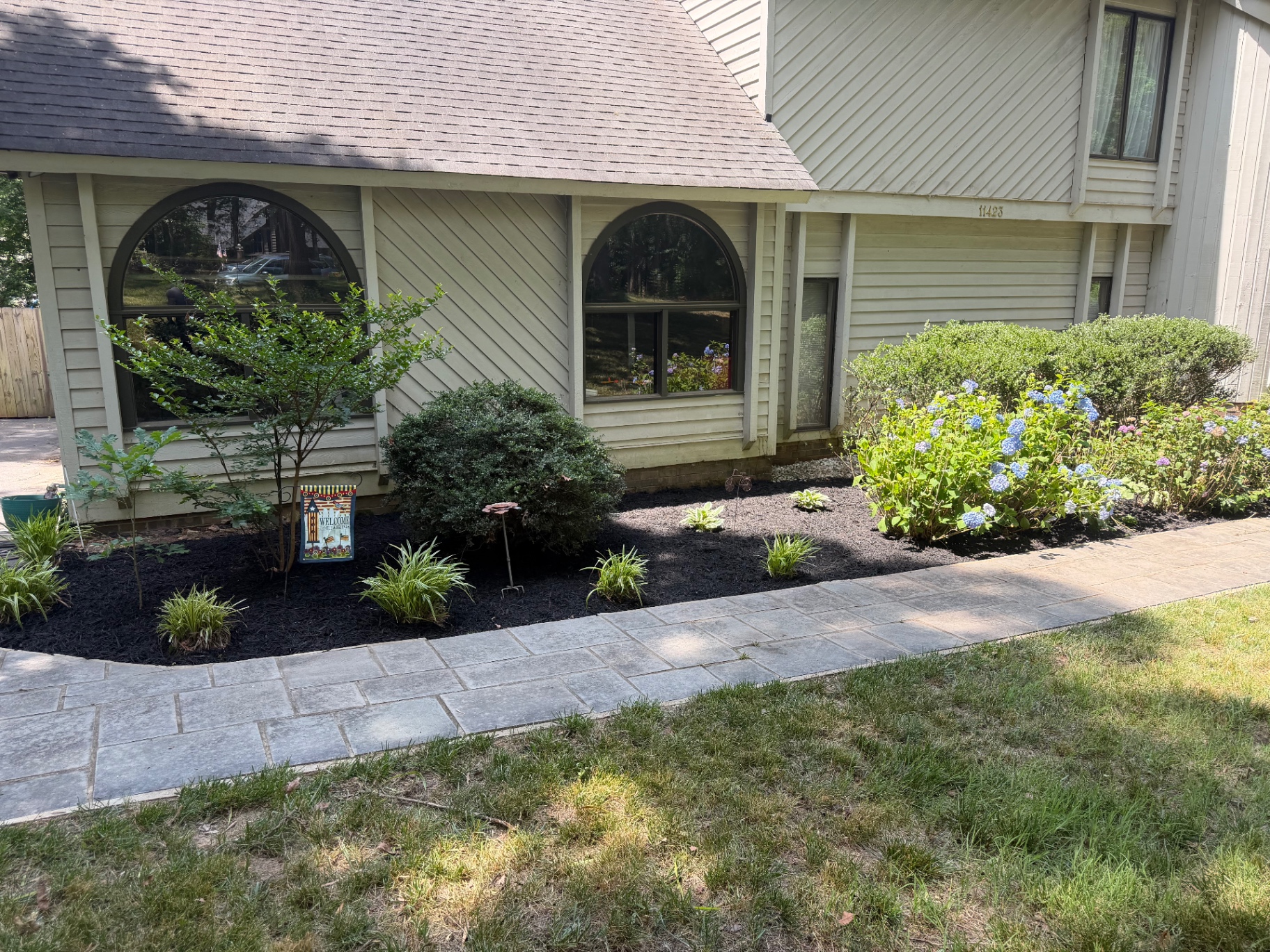 Fresh black mulch beds with sharp edging along a paver walkway